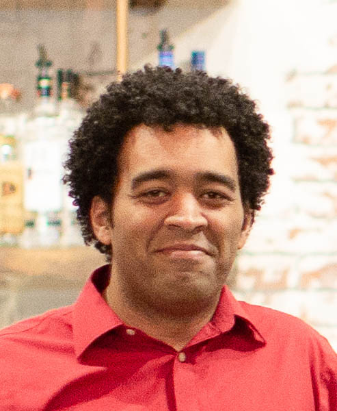 A man wearing red shirt and smiling and with a blurry background